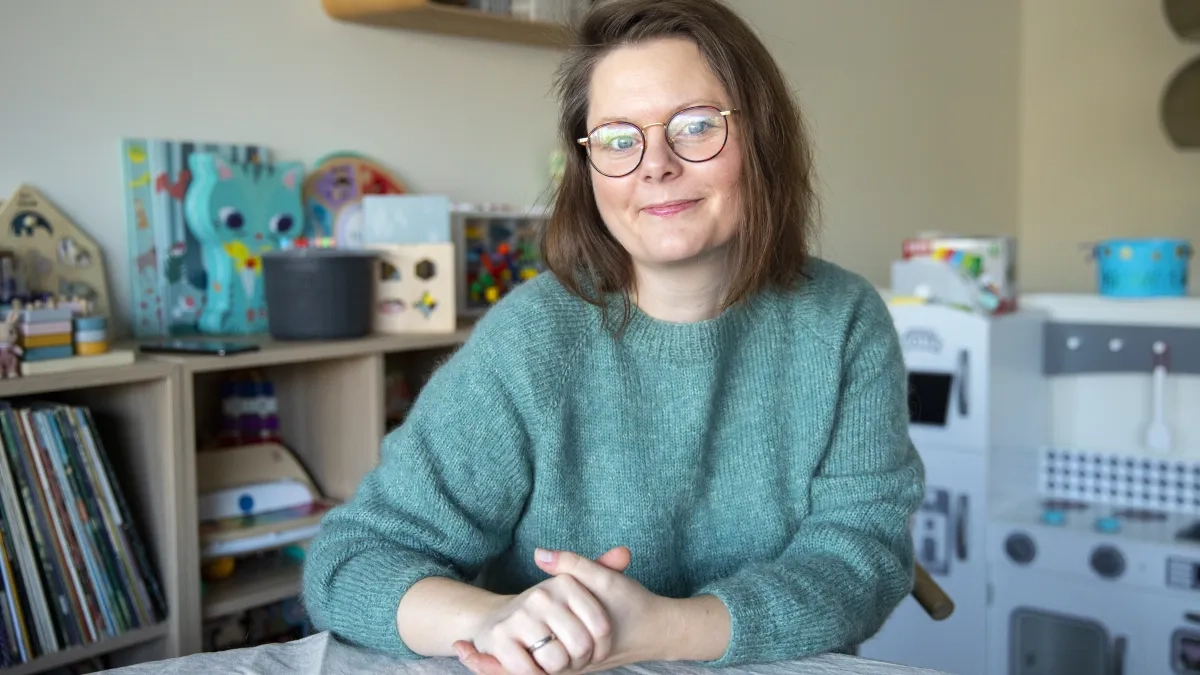 Ann Helen sitter ved et bord og ser p&aring; kameraet